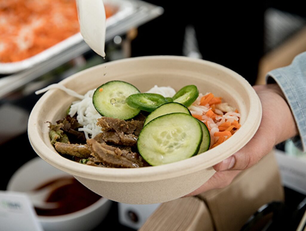 A hand holding a Lish individual meal bowl filled with rice, vegetables, and protein.